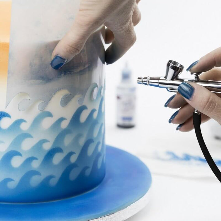 Närbild på airbrush sprutpistol med färgkopp för detaljerad tårtdekoration