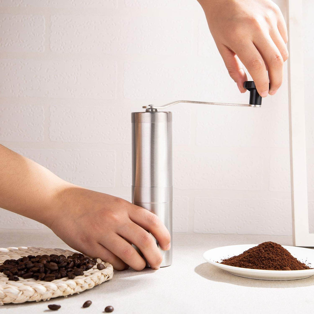Närbild på manuell kaffekvarn i rostfritt stål, framhäver dess portabla och robusta konstruktion.