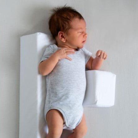 Baby sover tryggt på anti-rullningskudde, vit och grå, för optimal säkerhet och komfort