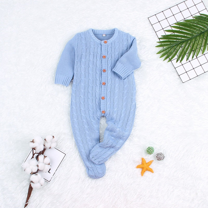 Närbild av de fina stickade detaljerna på en babyromper, accentuerar kvalitet och design.