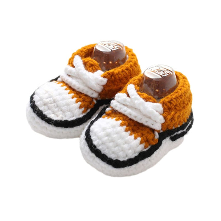 Ett par vita baby stickade snörskor liggandes bredvid en nallebjörn, mysigt för spädbarnsfötter