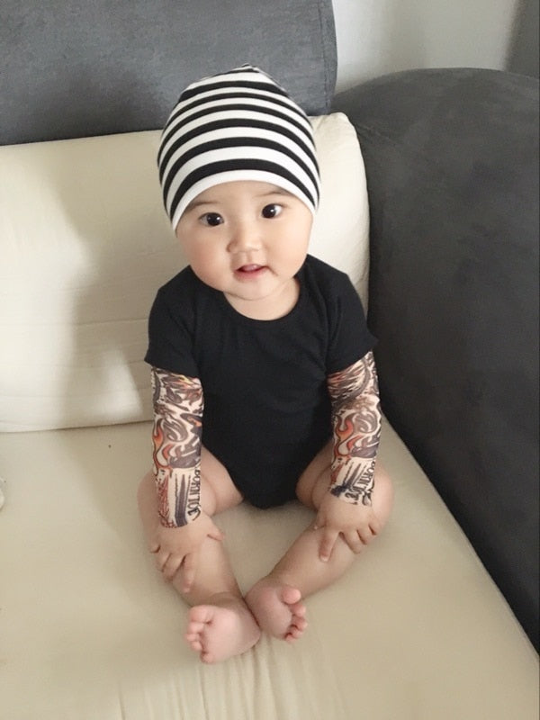 Rockig babybody med tatueringstryck på ärmarna, idealisk för unika barnkläder.