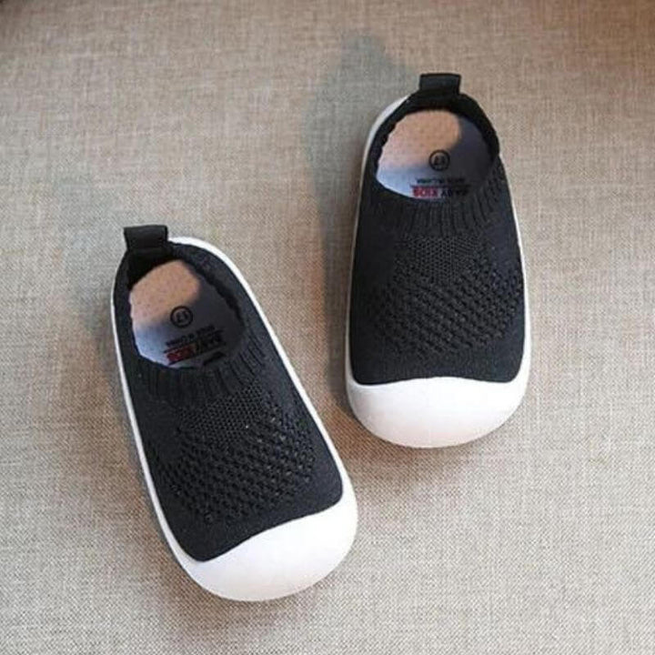 Vit bakgrundsbild av babyskor med andningsbart nät och robust halkfri sula.