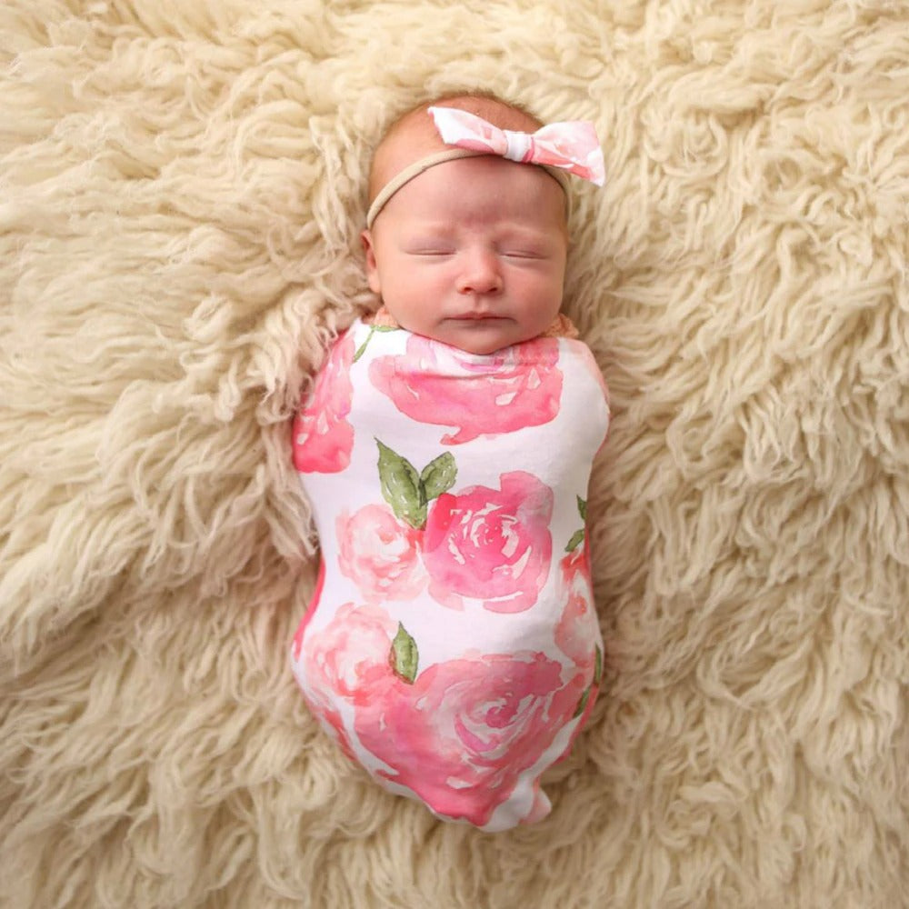 Nyfödd i mjuk babyswaddle och matchande huvudband, säker sömn
