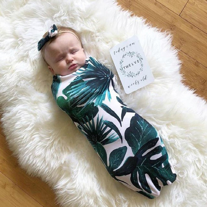 Flickbebis sover lugnt i mjuk babyswaddle och bomullshuvudband