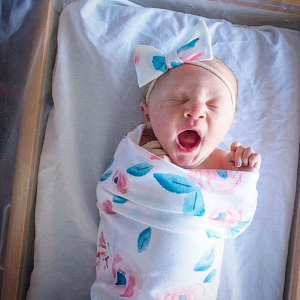 Pojkbebis insvept i mysig vit swaddlefilt och sött huvudband