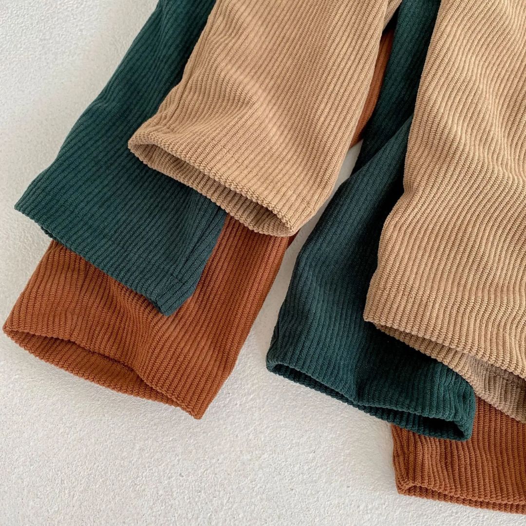 Liten tjej i Corduroy Set, sitter på marken, andningsbar och mjuk overall