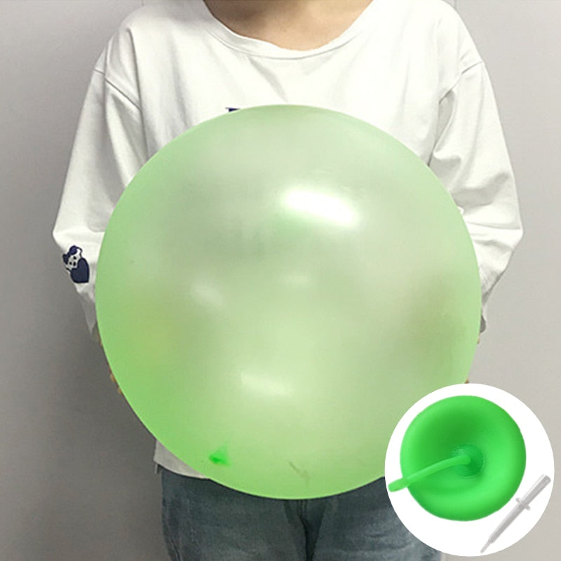 En stor klarblå bubbelboll ligger på gräset, redo för barnens sommarlek och fest