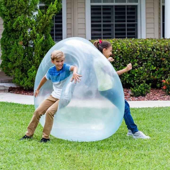 Glad familj spelar med en uppblåsbar bubbelboll i parken, perfekt för trädgårdslek och barn