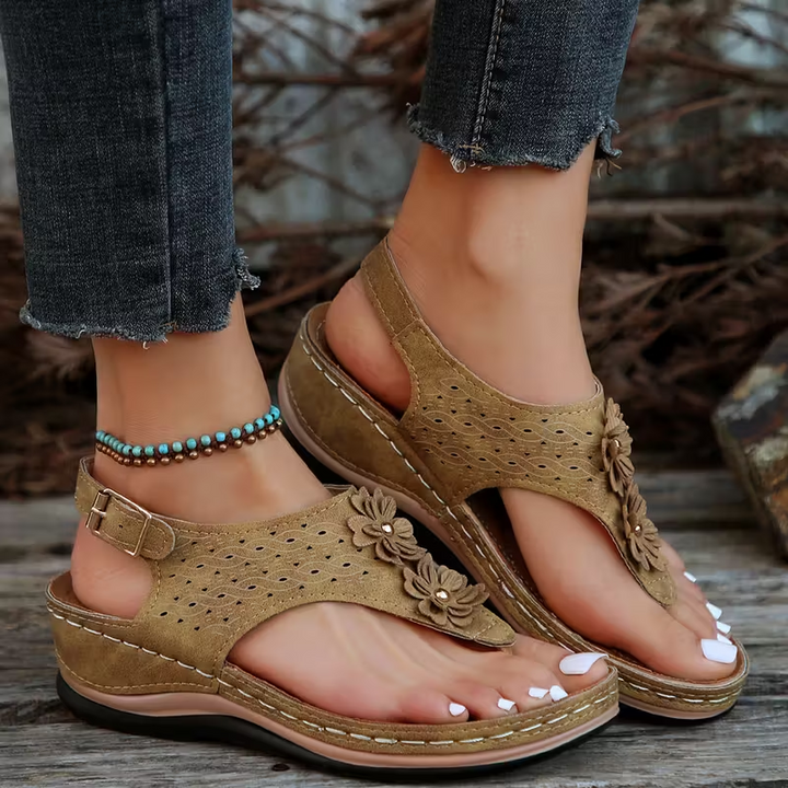 Kvinna bär bekväma strandsandaler med tofsar & kilklack. Idealiska sommarskor för en stilren look.