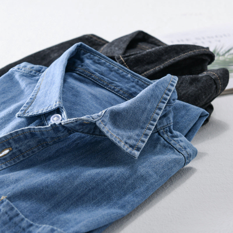 Detaljerad bild av en klassisk blå herrskjorta i jeans, visar tygets struktur och knappar.