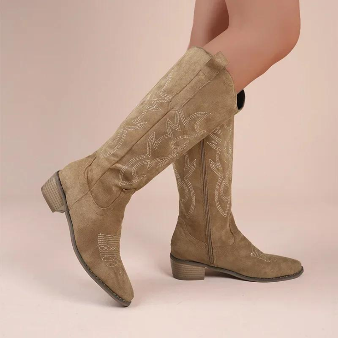 Närbild av detaljerad brodyr på eleganta knähöga cowboy-stövlar för dam. Unika westernboots.