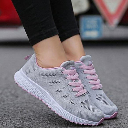 Par av lätta andningsaktiva damsneakers placerade på en ljus yta, redo för användning och fritidsträning.