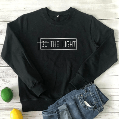 Närbild av "Be the Light" tryck på bekväm dam sweatshirt. Långärmad tröja i bomull/polyester för vardagen.