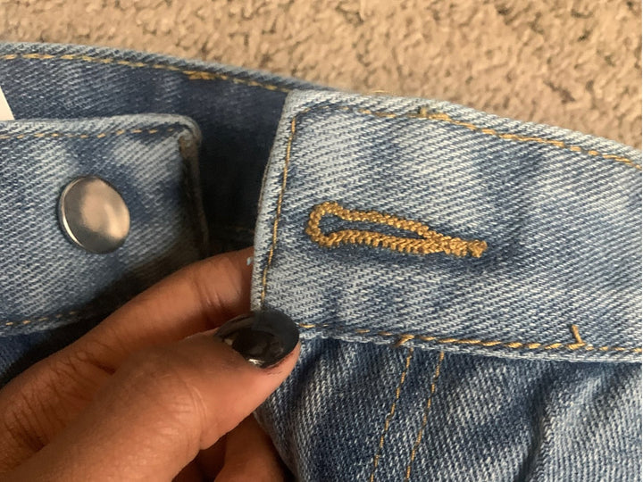 Detaljbild på ficka och tyg av dam baggy jeans, hög midja, vintage-känsla med modern komfort.