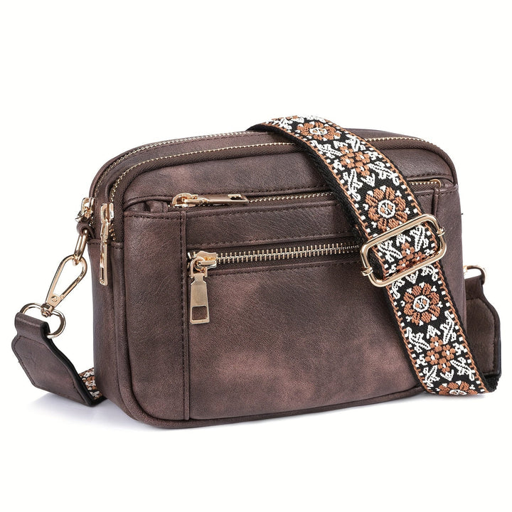 Detaljbild av spänne och justerbar rem på en damernas crossbody-väska i brun läderlook.