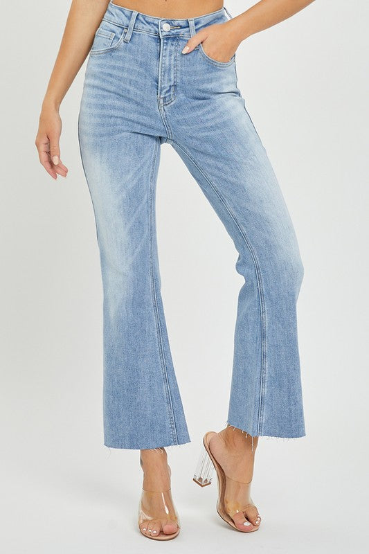 Närbild på ljus denimtyg av damjeans med hög midja, visar cropped flare-detalj.