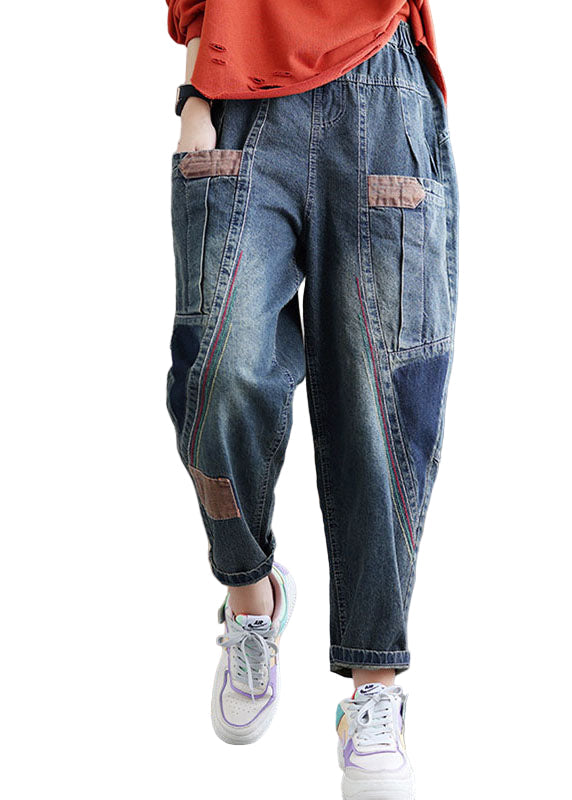 Detaljbild av trendiga damdenimbyxor med patchwork och praktiska fickor, visar unika sömmar.