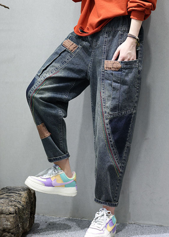 Närbild på tyget av denimbyxor för kvinnor som visar den detaljerade patchworkdesignen och strukturen.