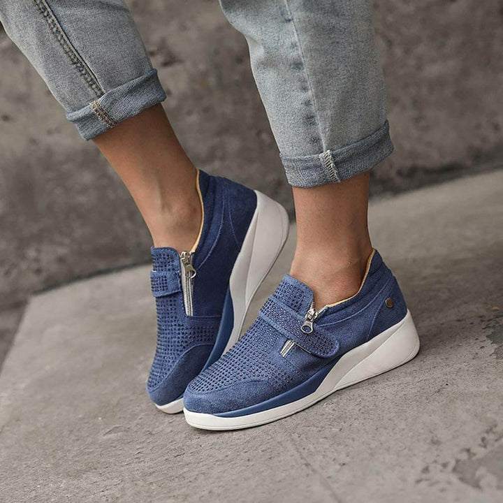Detaljbild på dragkedjan på damsneakersen, framhävandes den praktiska funktionen och stilen.