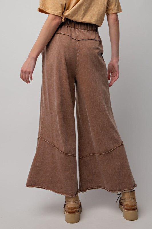 Modell bär bekväma bruna damvida byxor med elastisk midja, gjorda av mineraltvättad terry knit.