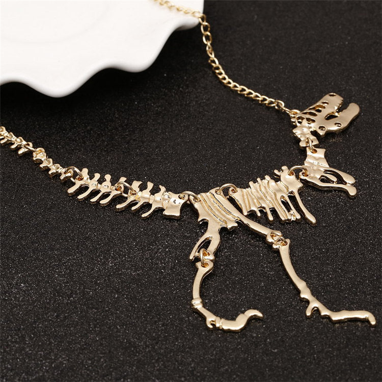 Stilrent unisex T-Rex skelett halsband i guld/bronsfärgad zinklegering. Coolt dinosauriesmycke.