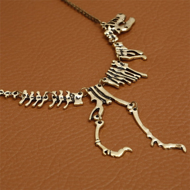 Närbild av unikt T-Rex skelett halsband i bronsfärgad zinklegering. Detaljerat dinosauriesmycke.