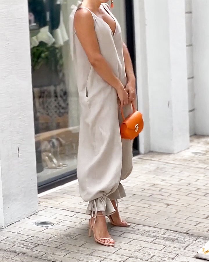 Ärmlös beige byxdress för dam med elegant v-hals. Smickrande passform som passar perfekt för sommarens evenemang.