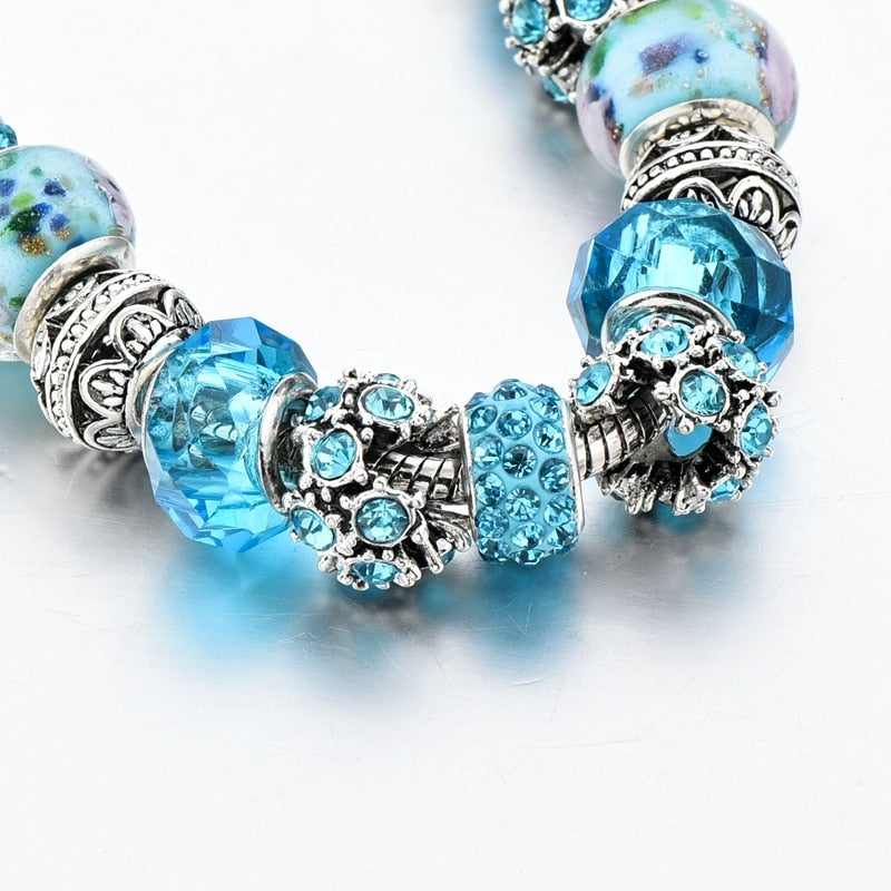 Detaljbild av blått kristallarmband som framhäver den intrikata designen och berlockerna.