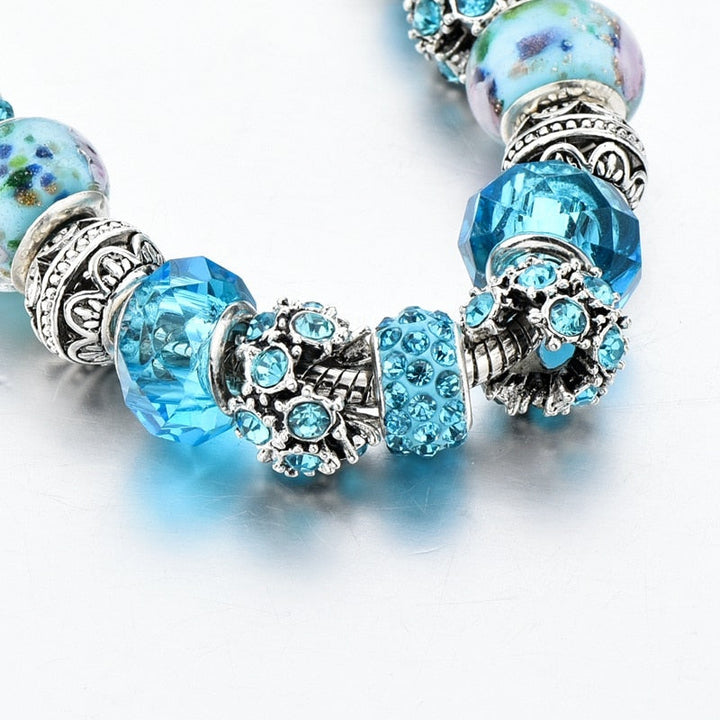 Detaljbild av blått kristallarmband som framhäver den intrikata designen och berlockerna.