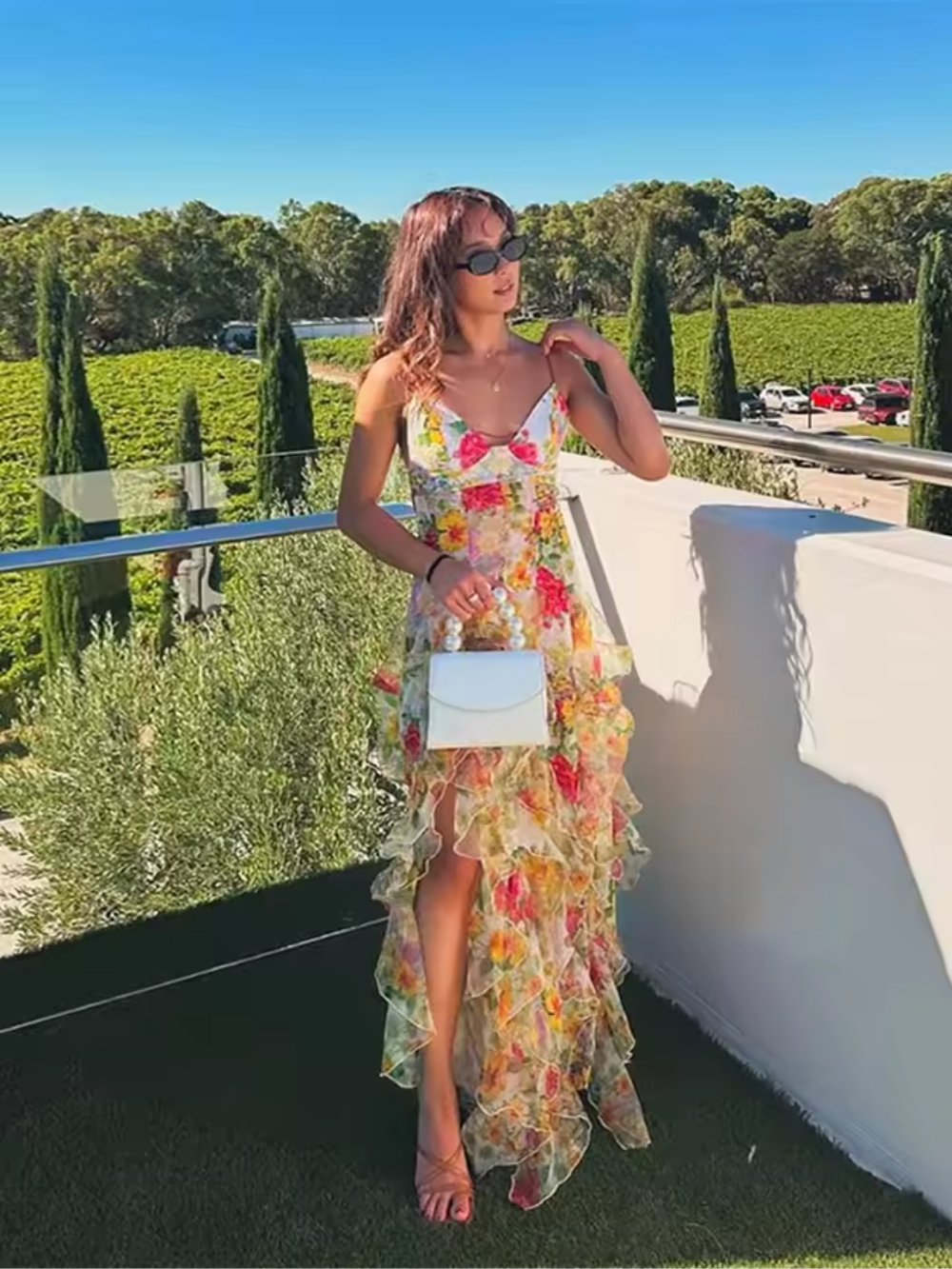 Produktbild av blommig volangklänning på galge. En färgstark och elegant kvinnors klänning redo för sommar.