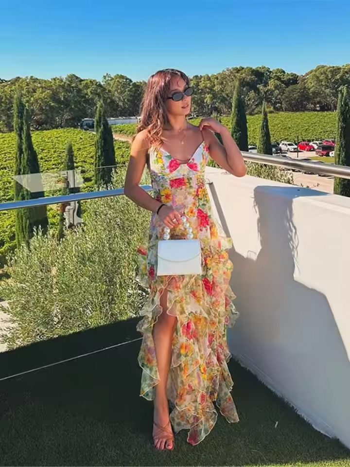 Produktbild av blommig volangklänning på galge. En färgstark och elegant kvinnors klänning redo för sommar.