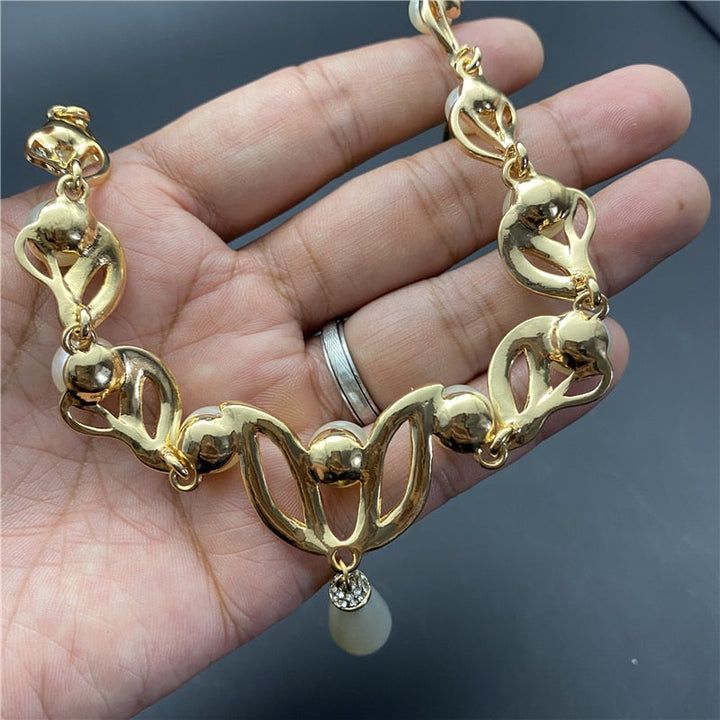 Brudsmyckesset liggandes på sammet: guldpläterade strass & pärlor som glimmar, eleganta accessoarer.
