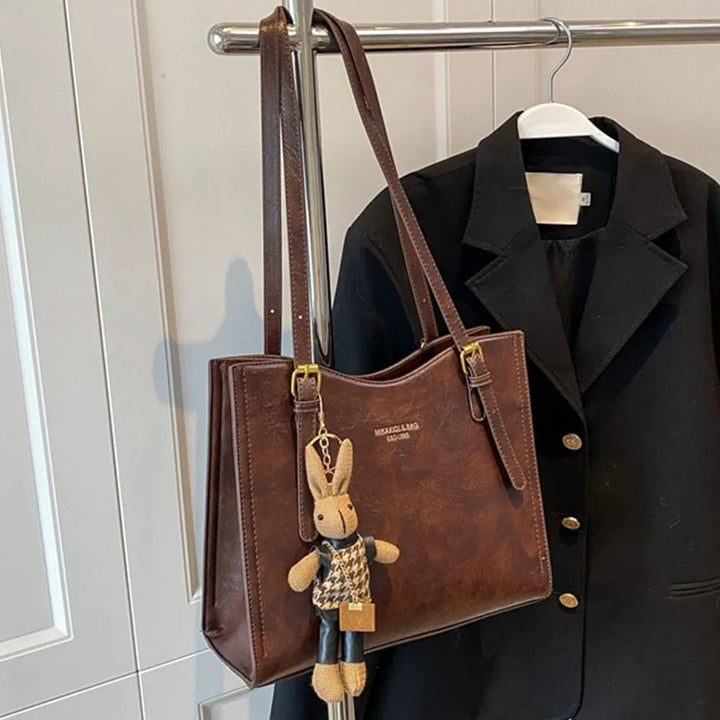 Rymlig toteväska i elegant design med charm. Praktisk damväska som kombinerar stil och funktion.