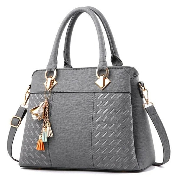 Elegant damväska i mörkbrun ton med guldiga detaljer och tofs, idealisk för crossbodybruk.