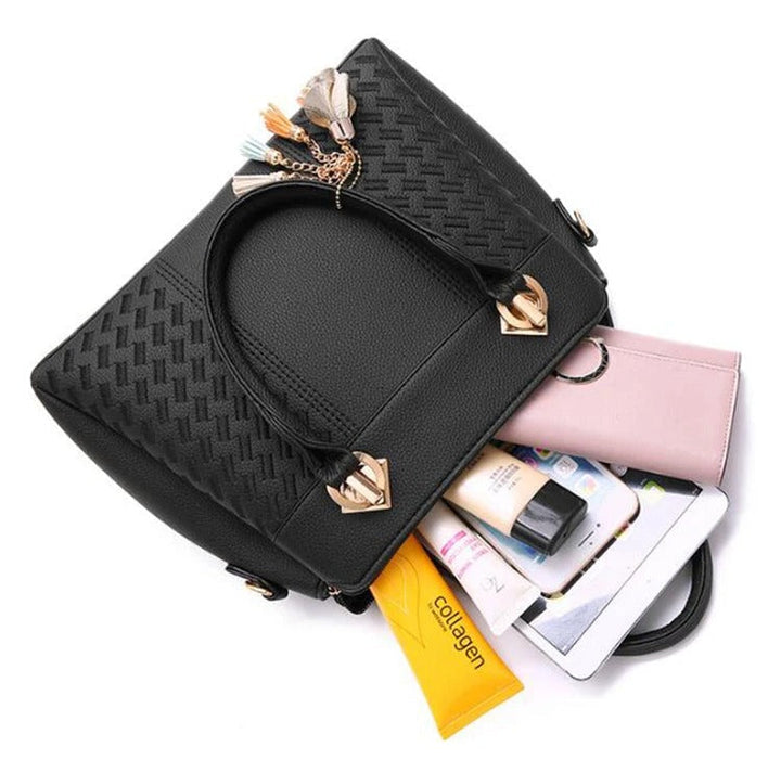 Elegant svart crossbodyväska med dragkedja och främre fack, prydd med tofs och broderi.