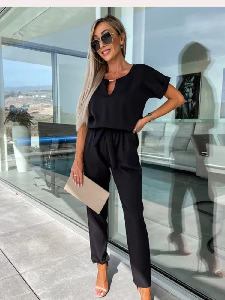 Svart, bekväm dam jumpsuit med V-hals, kort ärm och stretchig elastisk midja. Avslappnad stil.