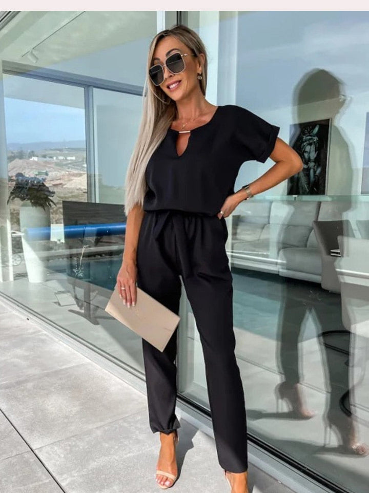 Svart, bekväm dam jumpsuit med V-hals, kort ärm och stretchig elastisk midja. Avslappnad stil.