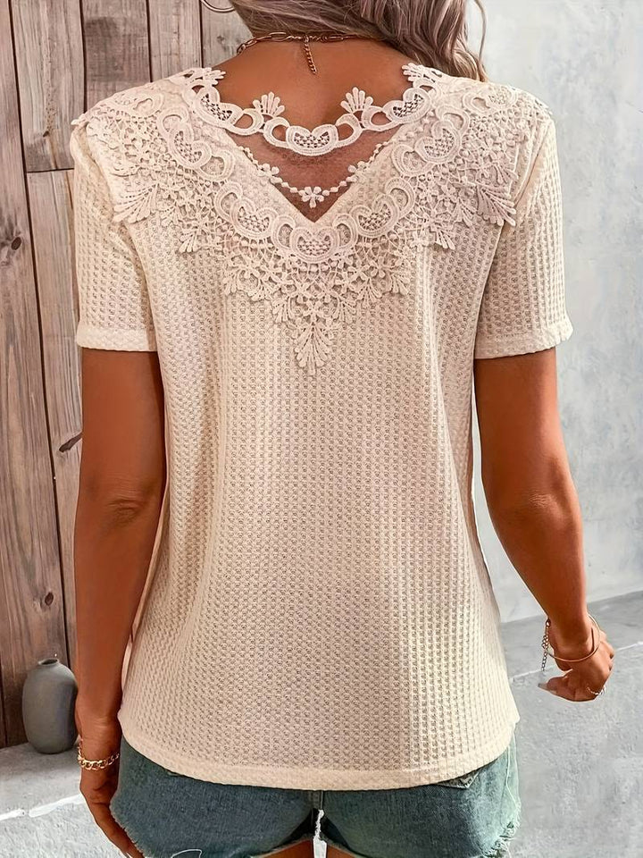 Modell bär elegant dam t-shirt med spets. Bekväm festtopp & stilren vardagsklädsel för kvinnor.