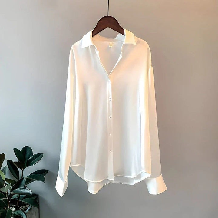 Närbild på ärmslutet av en damblus i silkesstil, visar manschetten med knappar, klassisk detalj.