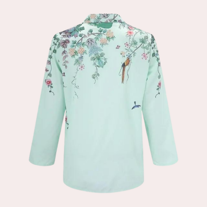 Detaljbild på blommönstret och puffärmen på den eleganta damblusen.