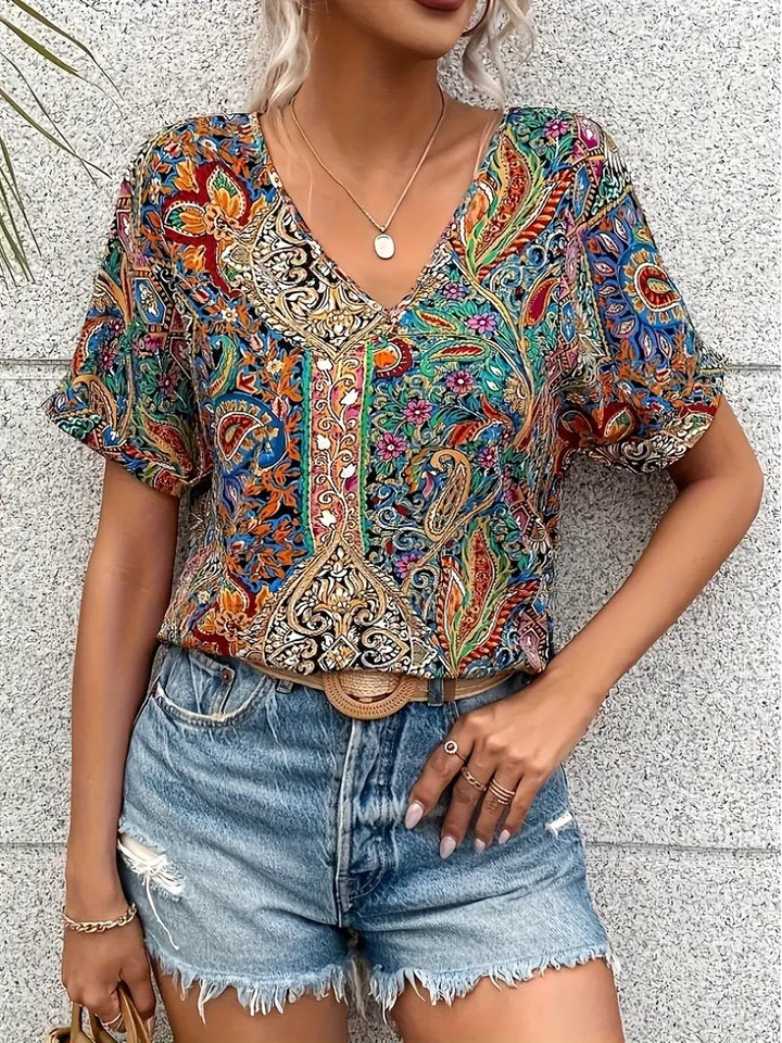 Elegant damblus med v-ringning och iögonfallande paisleymönster, perfekt som sommar- eller kontorsblus.