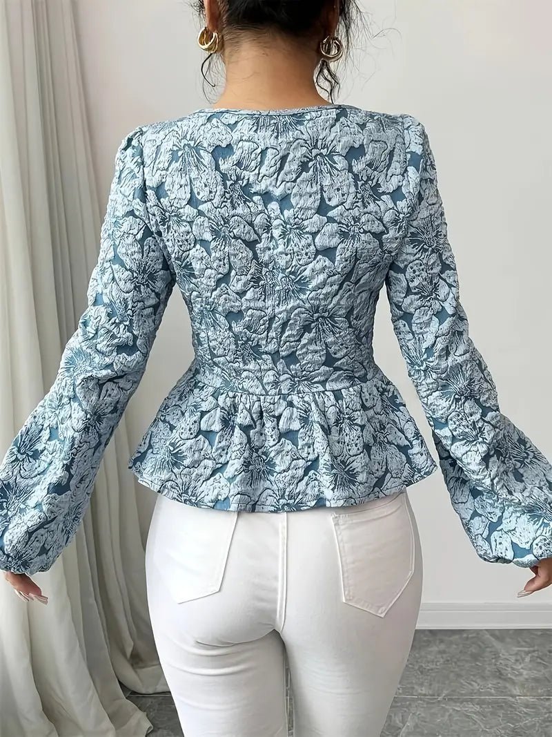Detaljbild: Elegant damblus i polyester med livfullt blommönster och voluminösa puffärmar.