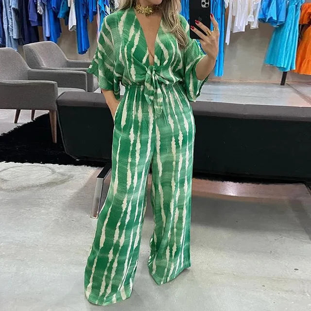 Svart damjumpsuit med djup V-ringning, vida ben. Avslappnad men elegant byxdress för fest & sommar.