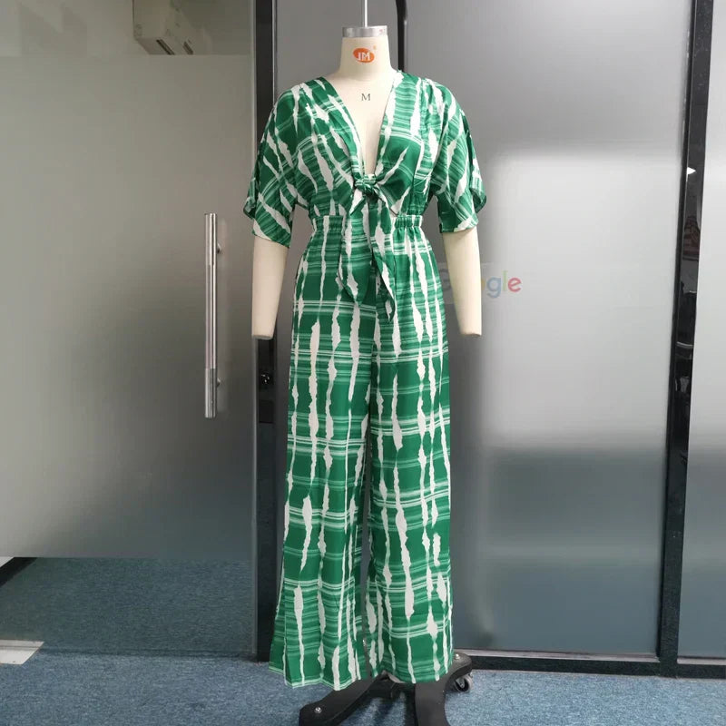 Grön damjumpsuit med djup V-ringning, bekväma breda ben. Mångsidig elegant byxdress för alla tillfällen.