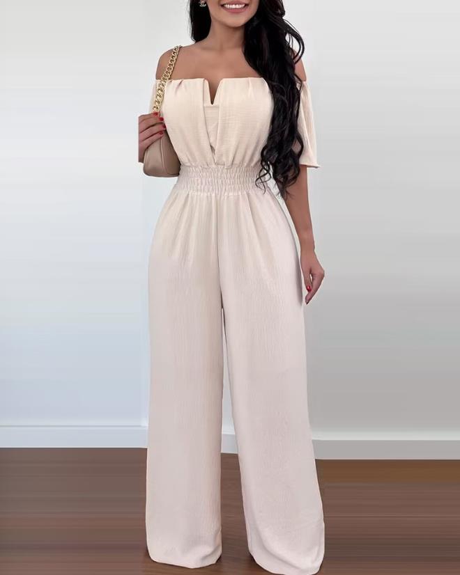 Modell bär off-shoulder damjumpsuit. Elegant veckad byxdress som ger en trendig & bekväm sommarstil.