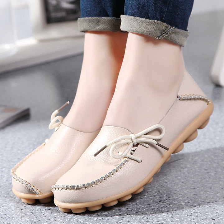 Flickans fötter i trendiga svarta PU-läderloafers, som framhäver den bekväma designen.
