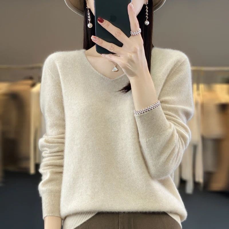 Modell som bär en beige damtröja i ullstil med v-ringning, kombinerat med jeans.
