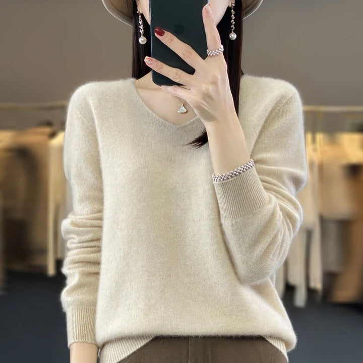 Modell som bär en beige damtröja i ullstil med v-ringning, kombinerat med jeans.