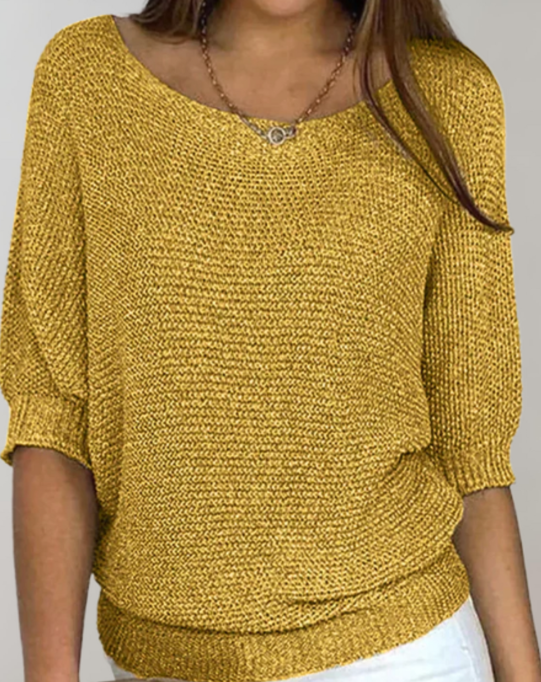 Kvinna i stilren damtopp med rund hals och mellanlånga ärmar. Elegant vardagsmode för alla tillfällen.